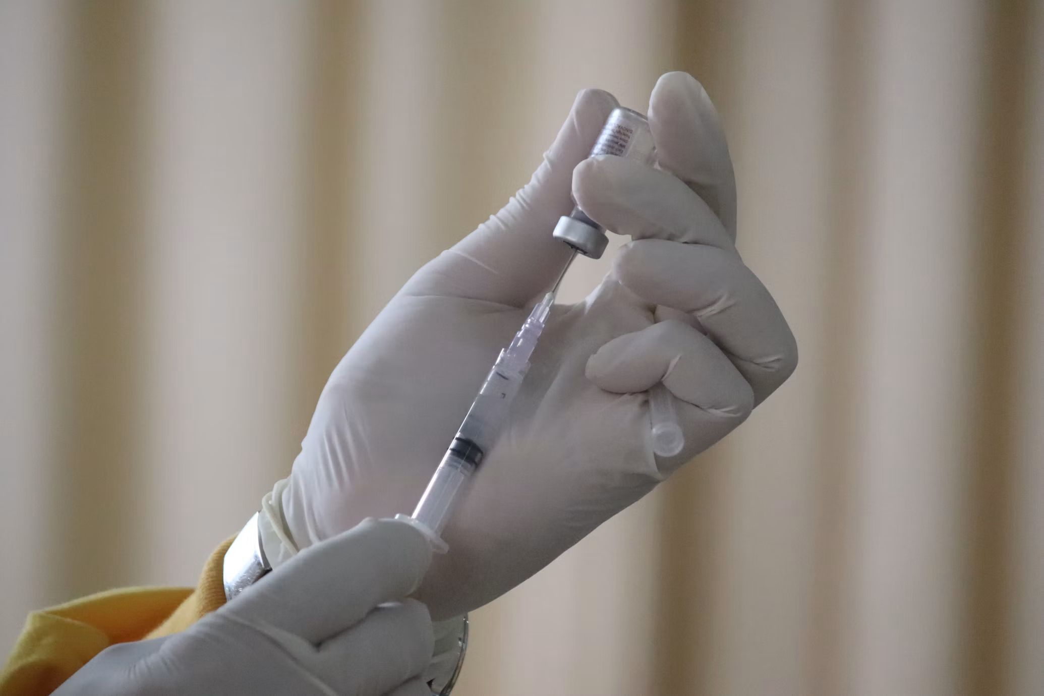Gloved hands drawing up an injection from a vial